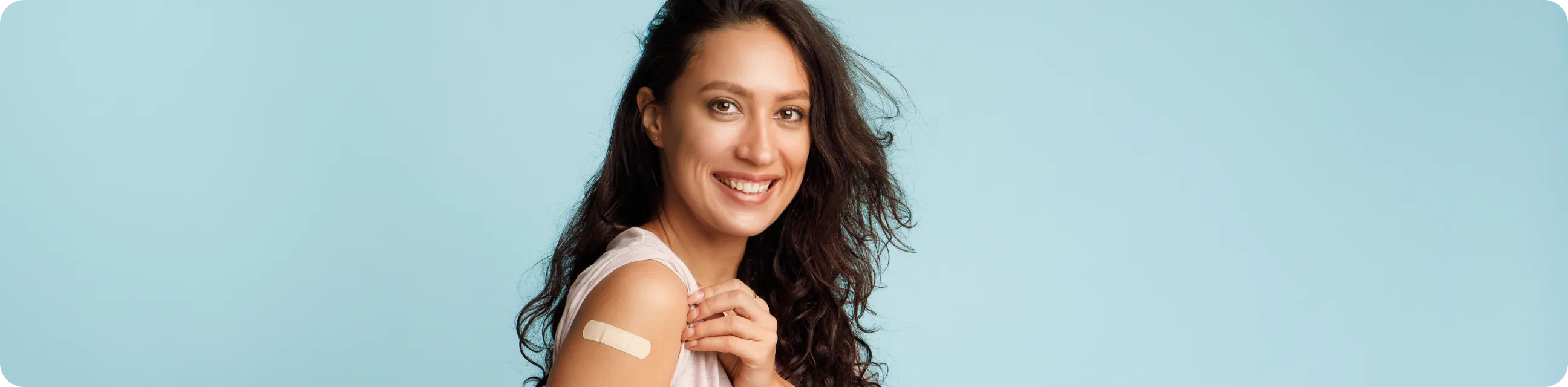 Mujer mostrando su brazo con una curita después de recibir una vacuna