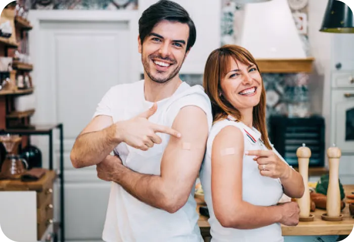 Hombre y mujer mostrando su brazo con la manga arremangada y una curita en el lugar donde le aplicaron la vacuna